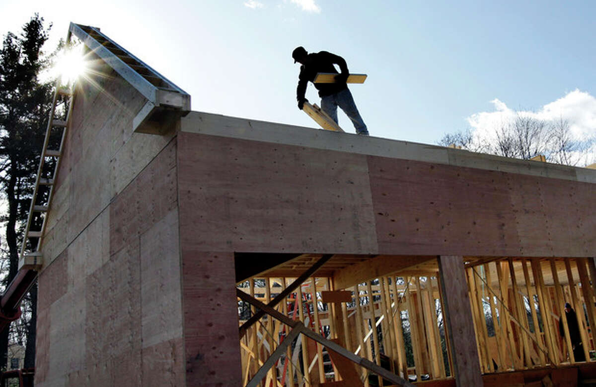 In this Feb. 13, 2012 photo, a builder works on a new single-family home in North Andover, Mass. U.S. homebuilders are gradually growing more optimistic about the depressed housing market and believe homes sales could pick up sharply at the beginning of 2012. (AP Photo/Elise Amendola)