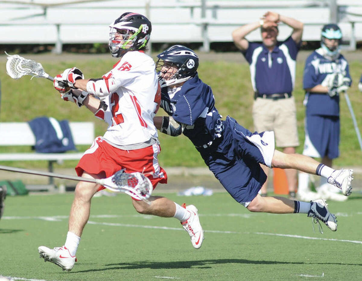 Will Kelley of Wilton, right, dives to knock the ball out of the stick of a Fairfield Prep player during Friday's game at Fairfield University.