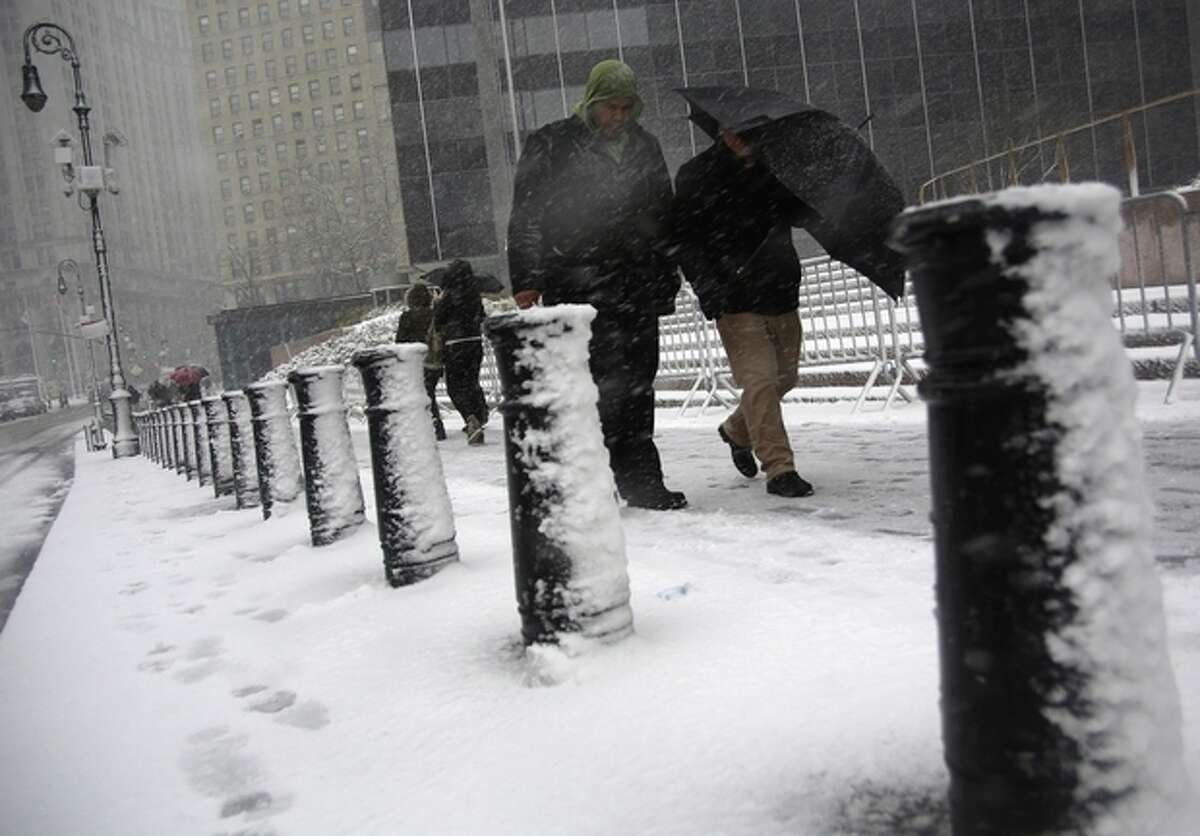 People shield themselves from driving snow in Foley Square during a storm on Friday, March. 8 2013, in New York. A very wet snow is causing slippery road conditions in the metropolitan area and several inches have fallen on eastern Long Island and Westchester, Rockland and Putnam counties.(AP Photo/Peter Morgan)