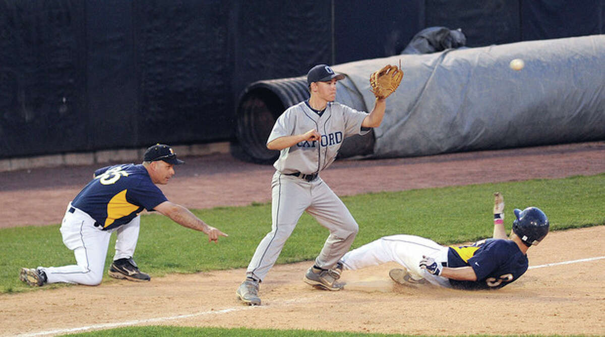 Hour photo/John Nash Weston head coach Frank Fedeli, left, points to where his Trojans baserunner Max Molinsky should slide as Oxford third baseman Dale Keller awaits the throw in the third inning of Saturday night's SWC baseball game at the Ballpark at Harbor Yard in Bridgeport.