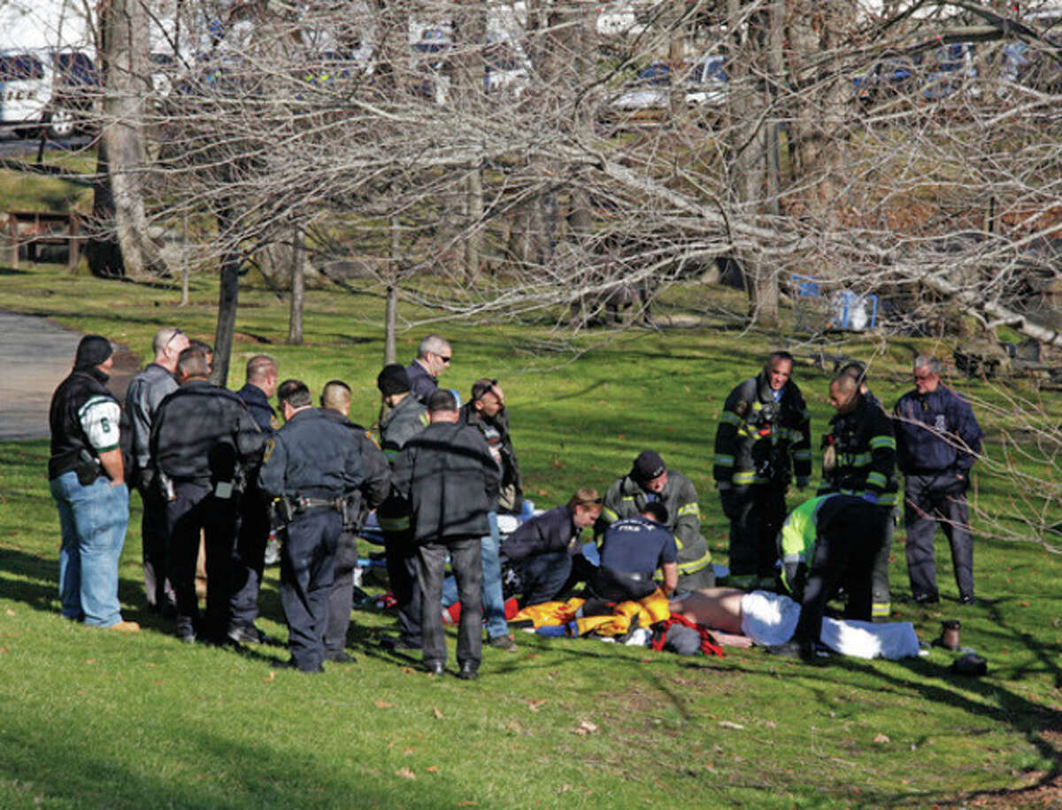 Hour photo / Danielle Robinson A rescue crew performs CPR on a body that was found in the Five Mile River Saturday afternoon near the Darien/Norwalk line on Connecticut Avenue. Below, a rescue crew wheels away