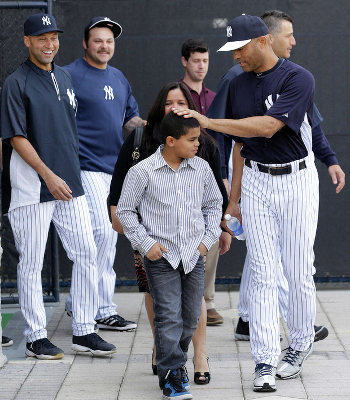 New York Yankees shortstop Derek Jeter, far left, and reliever Joba Chamberlain, second from left, watch as pitcher Mariano Rivera, far right, pats his son Jaziel on the head before a news conference announcing his plans to retire at the end of the 2013 season at Steinbrenner Field Saturday, March 9, 2013, in Tampa, Fla. Yankees pitcher Andy Pettitte is behind Rivera. Rivera holds baseball's all-time saves leader. (AP Photo/Kathy Willens)