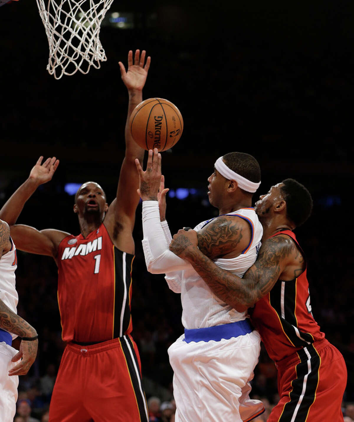 Miami Heat forward Udonis Haslem, right, holds New York Knicks forward Carmelo Anthony, center, as Heat center Chris Bosh (1) tries to block Anthony's shot during the first half of their an basketball game at Madison Square Garden in New York, Sunday, March 3, 2013. A foul was called on Haslem. (AP Photo/Kathy Willens)