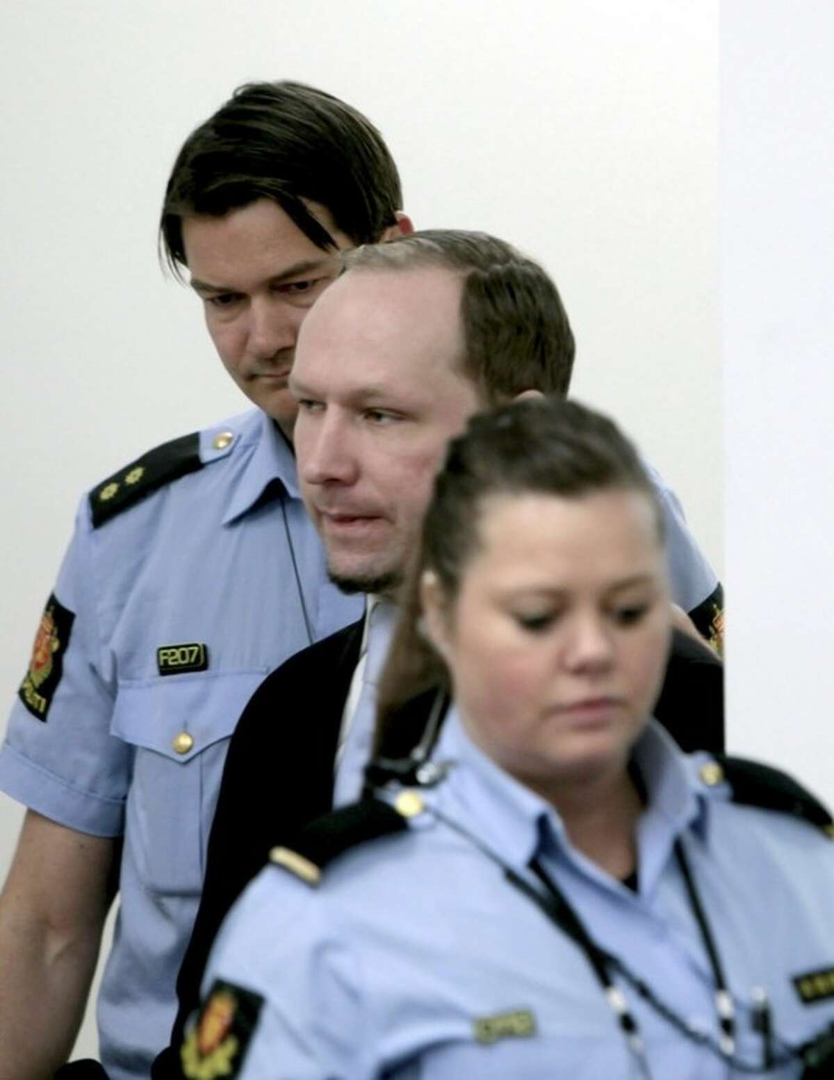 Anders Behring Breivik between 2 police officers prior to taking his seat after a break in the courtroom in Oslo Tuesday morning May 15, 2012. When the trial opened, the self-styled anti-Muslim crusader pleaded innocent to terror charges _ even though he admitted to the facts of the case _ saying he didn't recognize the authority of the court. (AP Photo/Stian Lysberg Solum, Pool)
