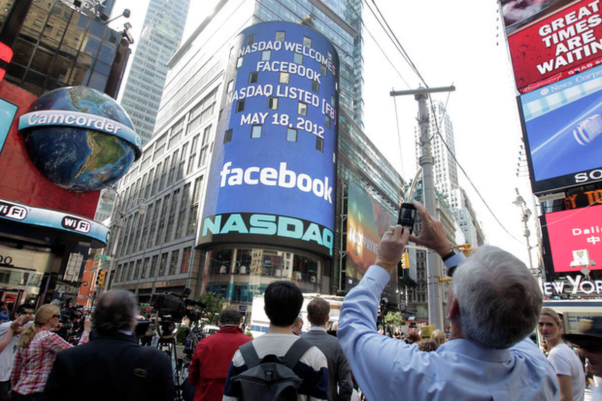 A man stops to photograph Nasdaq in Times Square as Facebook has its IPO, Friday, May 18, 2012, in New York. The social media company priced its IPO on Thursday at $38 per share, and beginning Friday regular investors will have a chance to buy shares. (AP Photo/Richard Drew)