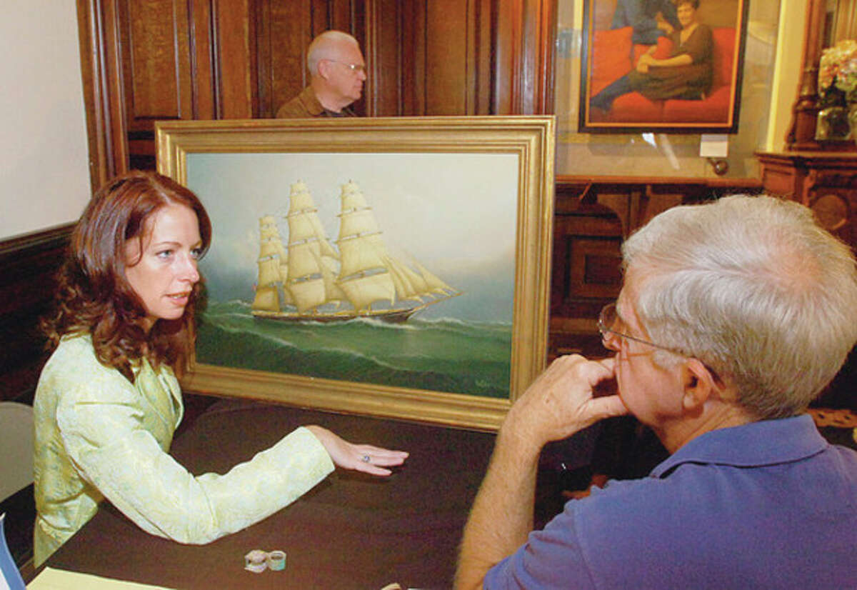 Hour photo / Erik Trautmann Christine Downing of Downing Auctions looks over a painting brought in to the second annual Antiques Appraisals Weekend at Lockwood Mathews Mansion Museum by James Buchta in this file photo.