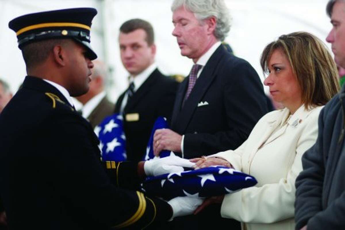 A member of a military honor guard gives the American flag that draped one of the 20 U.S. military veterans'' caskets whose remains were unclaimed to Michele McNaughton during their burial ceremony at Calverton National Cemetery, Saturday, Jan. 8, 2011, in Calverton, N.Y. McNaughton''s son Jimmy was the first New York City police officer to die in Iraq on Aug. 2, 2005. The ceremony, sponsored by the Dignity Memorial network, has provided services for more than 850 veterans since its inception in 2000. (AP Photo/Mary Altaffer)