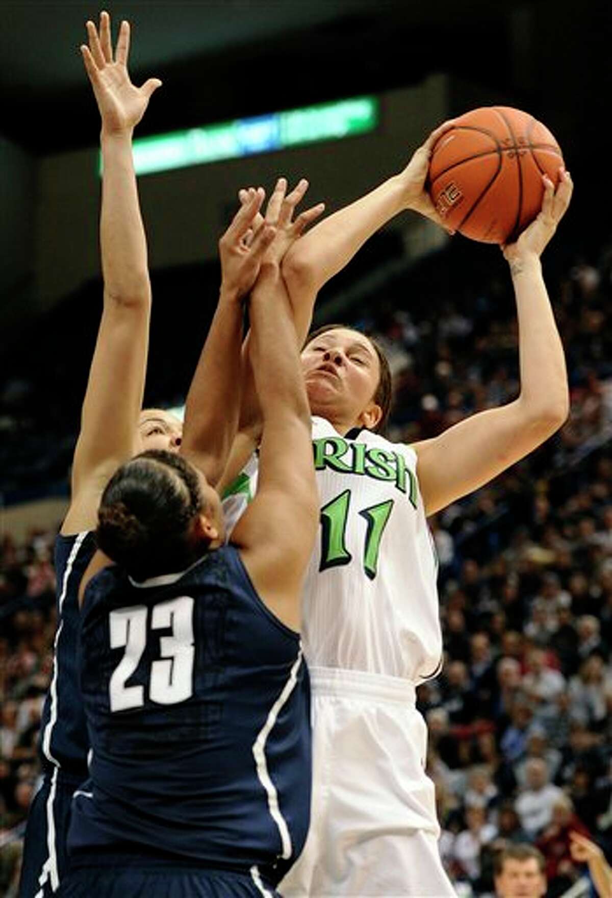 Notre Dame's Natalie Achonwa (11) goes up to the basket while guarded by Connecticut's Kaleena Mosqueda-Lewis (23) and Connecticut's Kiah Stokes, back, first half of an NCAA college basketball game in the final of the Big East Conference women's tournament in Hartford, Conn., Tuesday, March 12, 2013. (AP Photo/Jessica Hill)