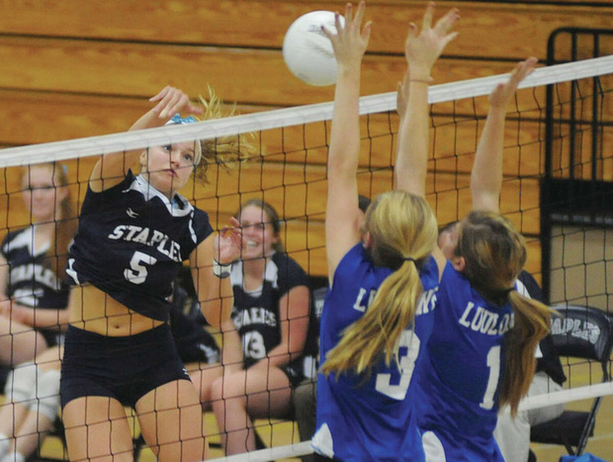 Hour photo/John Nash Staples outside hitter Anna Link spikes the ball toward two members of the Fairfield Ludlowe defense during Monday's game in Westport. Staples won, 3-0.