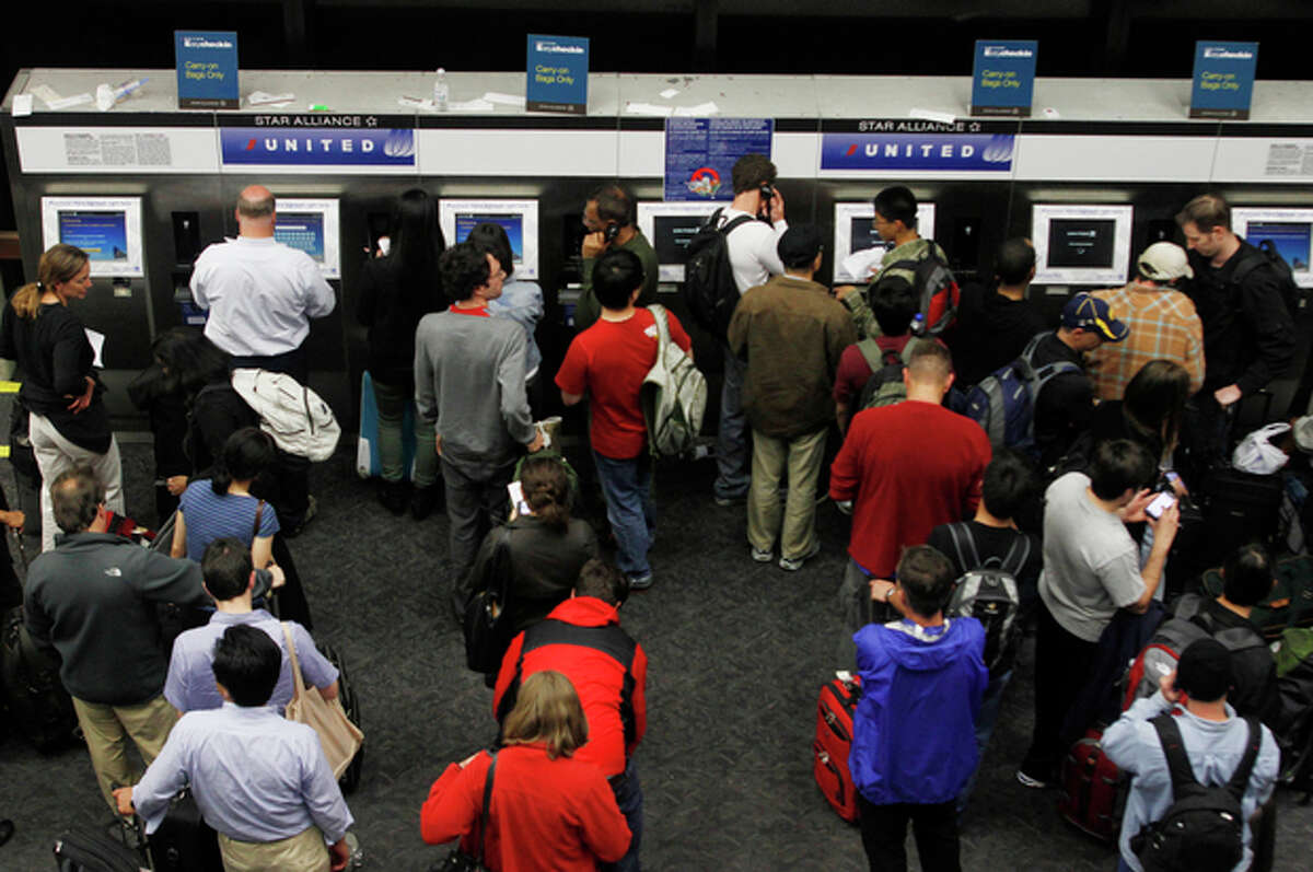 FILE - In this June 17, 2011, file photo, passengers crowd the kiosks to check in and print boarding passes at San Francisco International Airport in San Francisco. Airlines are setting aside more rows for passengers willing to pay extra for a better seat. That means families are going to struggle to sit next to each other unless they booked early or are willing to shell out anywhere from $5 to $180 extra, each way. (AP Photo/George Nikitin, File)