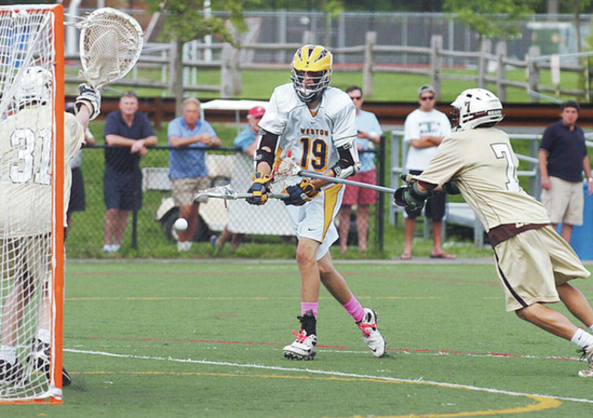 Hour photo/Erik Trautmann Weston's Lyle Mitchell, center, fires a shot at the Stonington goal during Saturday's Class S boys lacrosse state tournament quarterfinal game in Weston. Mitchell scored three goals and set up another as the Trojans advanced to a semifinal matchup against SWC rival Joel Barlow by beating Stonington, 8-6.