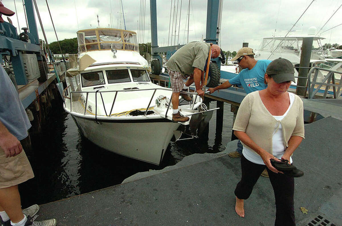 Photo by Alex von Kleydorff. Wilton's Claudia and Tom Bennett step off the bow of their 48-foot Sea Ranger Trawler, 'Another Fetish,' as a crew at Norwalk's Cove Marina lift it out of the water as hurricane Irene makes its way to New England.