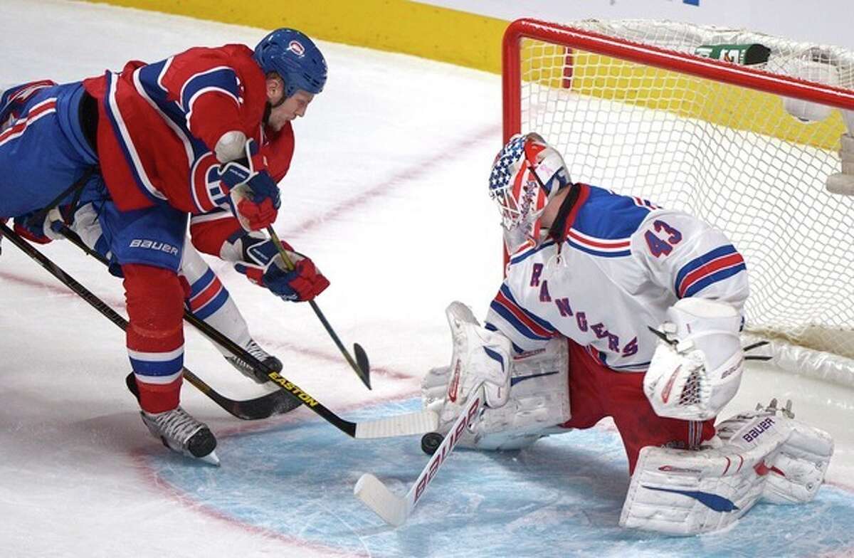 Montreal Canadiens' Travis Moen, left, moves in on New York Rangers goaltender Martin Biron, right, during second-period NHL hockey game action in Montreal, Saturday, March 30, 2013. (AP Photo/The Canadian Press, Graham Hughes)