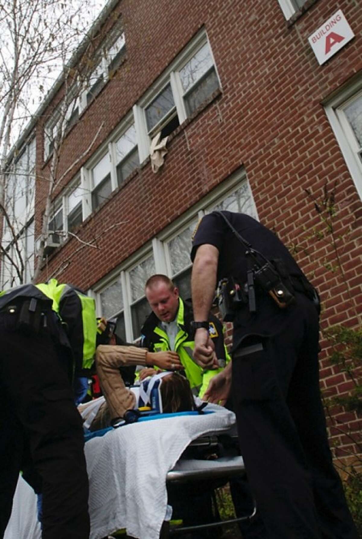 A woman is helped by emergency personnel after she jumps from her second story window when smoke from a cooking fire filled her apartment building on Strawberry Hill Ave Wednesday morning. Hour photo / Erik Trautmann