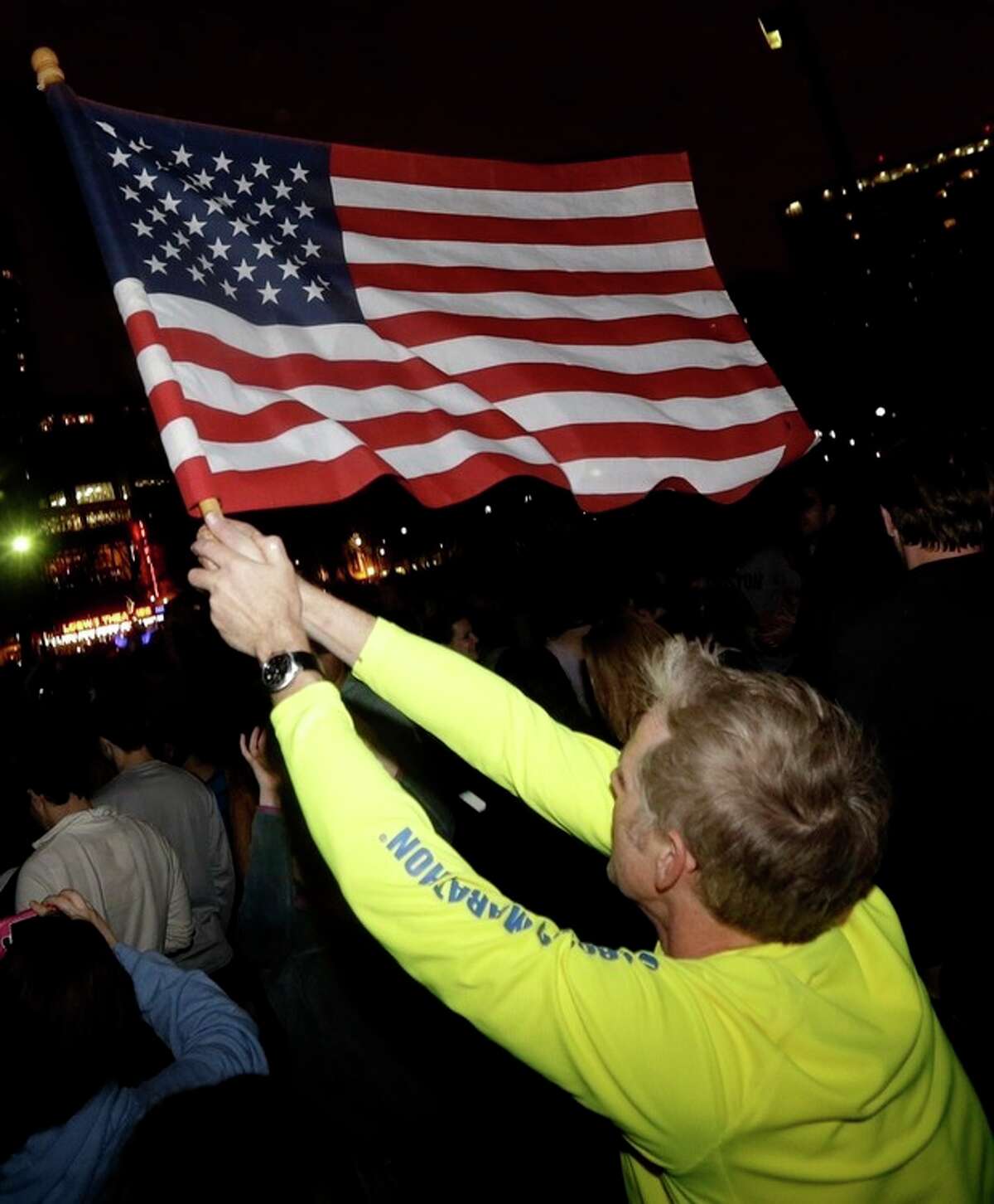 Frank McGillin, who ran three Boston Marathons, waves a U.S. flag as a crowd reacts to news of the arrest of one of the Boston Marathon bombing suspects during a celebration at Boston Common, Friday, April 19, 2013, in Boston. Boston Marathon bombing suspect Dzhokhar Tsarnaev was captured in Watertown, Mass. The 19-year-old college student wanted in the bombings was taken into custody Friday evening after a manhunt that left the city virtually paralyzed and his older brother and accomplice dead. (AP Photo/Julio Cortez)
