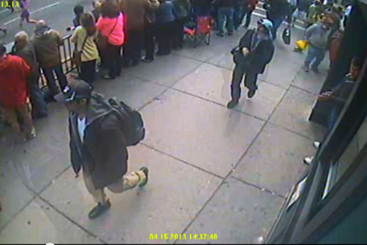 This image taken from video released by the FBI on Thursday, April 18, 2013 shows what the FBI are calling suspect number 1, front, in black cap, and suspect number 2, in white cap, back right, walking near each other through the crowd in Boston on Monday, April 15, 2013, before the explosions at the Boston Marathon. (AP Photo/FBI)