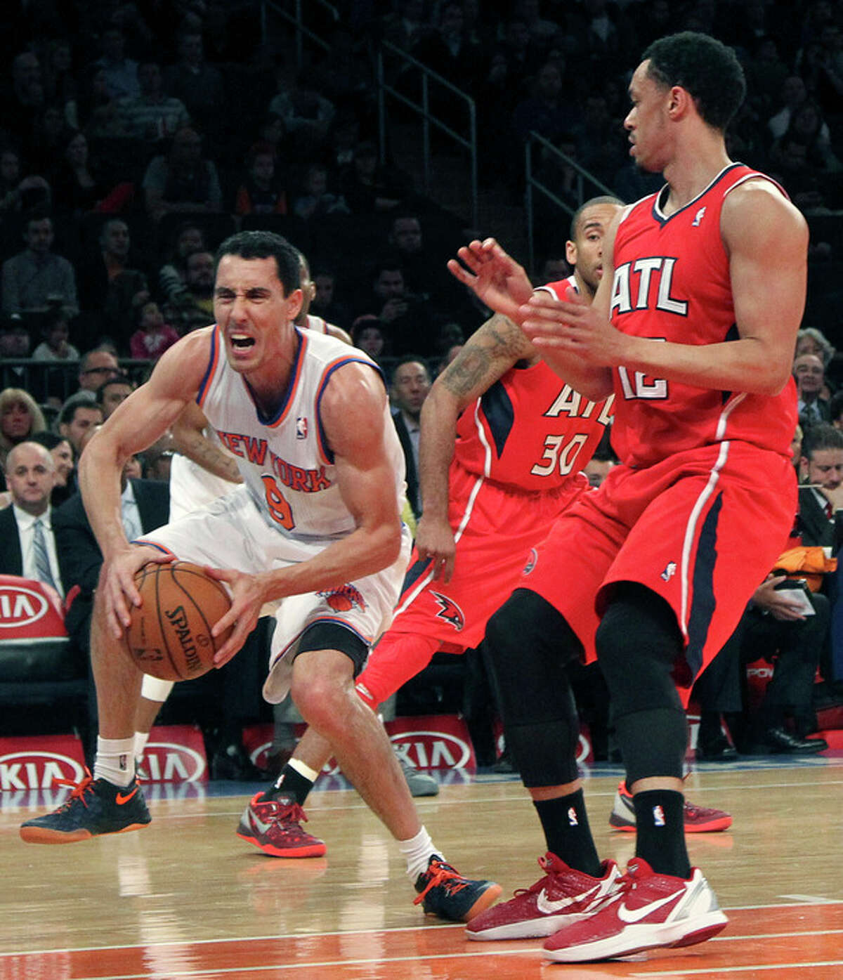 New York Knicks' Pablo Prigioni (9) grimaces as he injures his foot driving past Dahntay Jones (30) and Atlanta Hawks' John Jenkins during the first half of an NBA basketball game, Wednesday, April 17, 2013, at Madison Square Garden in New York. (AP Photo/Mary Altaffer)
