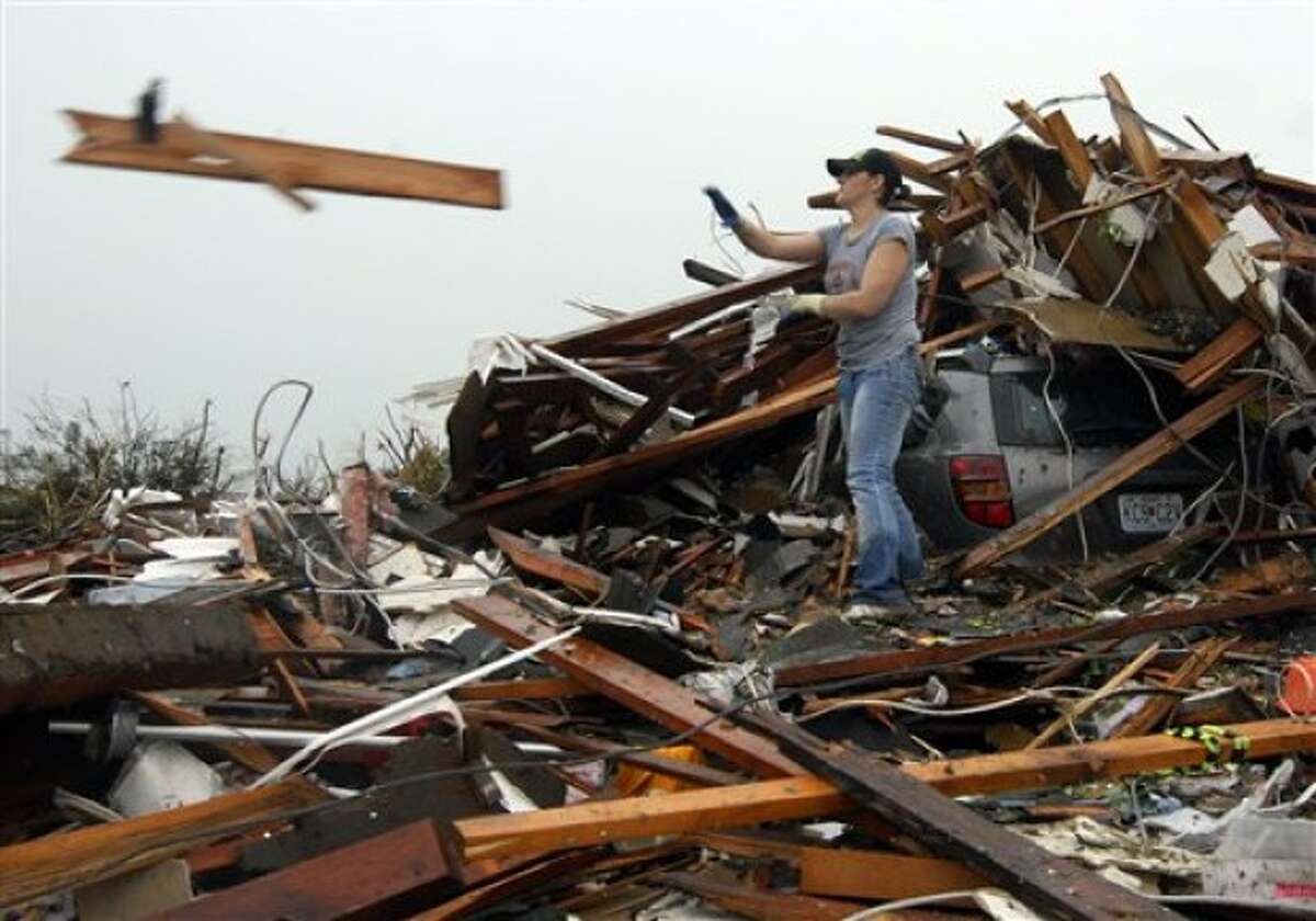 Sabrina Banspmer tosses a board from the destroyed home of her grandmother in Joplin, Mo, on Monday, May 23, 2011. Banspmer was doing what many Joplin residents were busy with on Monday, trying to salvage anything from their homes that were damaged or destroyed by the tornado that struck on Sunday. (AP Photo/Mike Gullett)