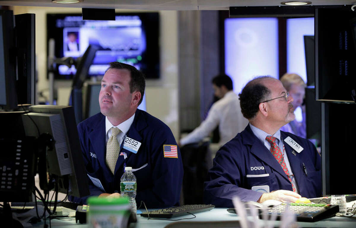 FILE- In this Tuesday, July 17, 2012, file photo, Specialists Charles Boeddinghaus, left, and Douglas Johnson, work at their posts on the floor of the New York Stock Exchange Tuesday, July 17, 2012. Renewed hope for more help from the Fed supported markets, as did positive earnings statements from Goldman Sachs, Coca Cola and Yahoo. U.S. earnings statements will remain a focus of attention later. (AP Photo/Richard Drew, File)