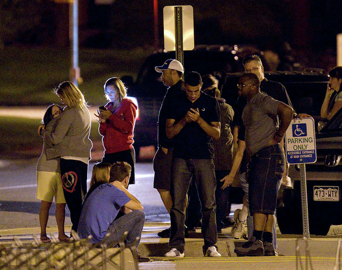 People use mobile devices as they wait outside Gateway High School where witnesses were brought for questioning after a shooting at a movie theater showing the Batman movie "The Dark Knight Rises," Friday, July 20, 2012 in Aurora, Colo. A gunman wearing a gas mask set off an unknown gas and fired into the crowded movie theater killing 12 people and injuring at least 50 others, authorities said. (AP Photo/Barry Gutierrez)