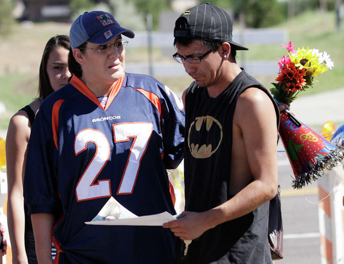 Shelly Fradkin, left, and Isaac Pacheo, right, cry as they look at photos of their friend Alex Sullivan, Saturday, July 21, 2012, as they visit a memorial near the movie theater in Aurora, Colo. Twelve people were killed and dozens were injured in the attack early Friday at the packed theater during a showing of the Batman movie, "The Dark Knight Rises." Police have identified the suspected shooter as James Holmes, 24. (AP Photo/Ted S. Warren)