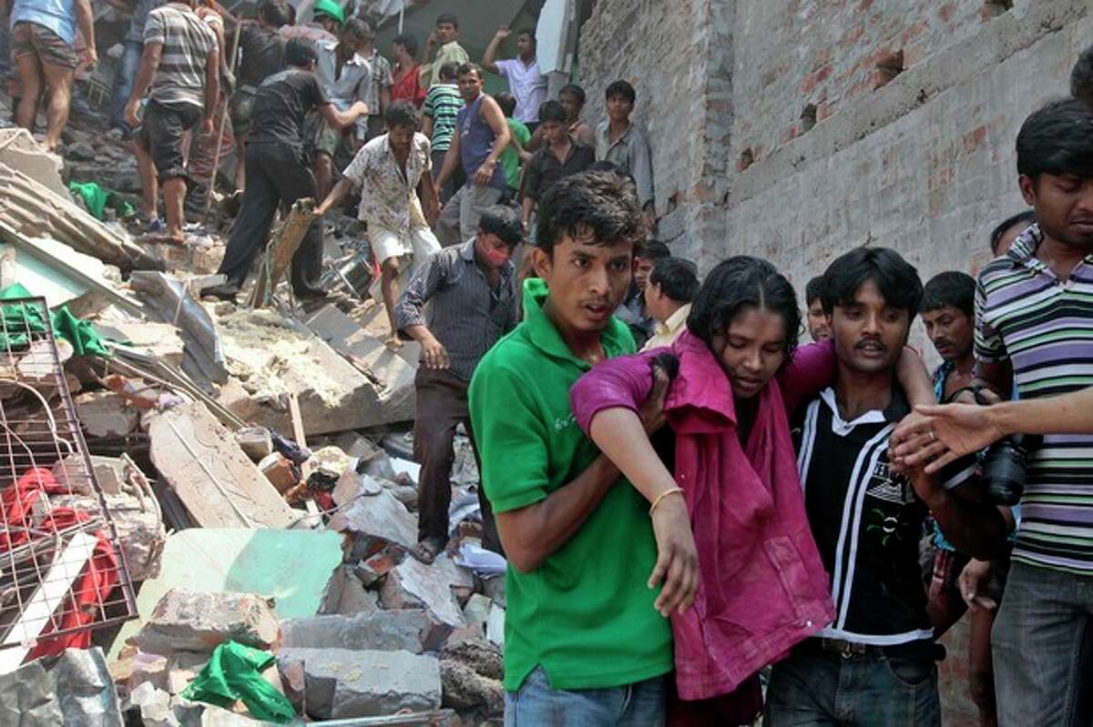 Rescuers assist an injured woman after an eight-story building housing several garment factories collapsed in Savar, near Dhaka, Bangladesh, Wednesday, April 24, 2013. Dozens were killed and many more are feared trapped in the rubble. (AP Photo/ A.M. Ahad)