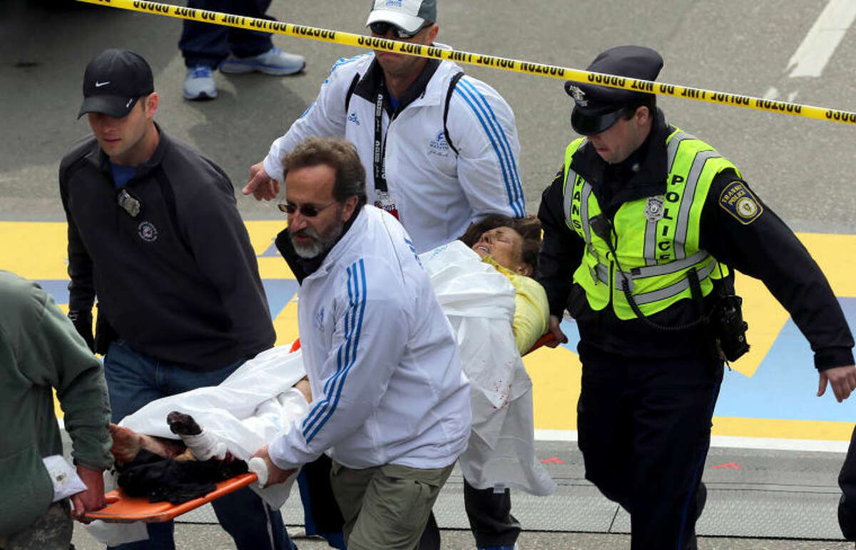 Medical workers aid injured people at the finish line of the 2013 Boston Marathon following an explosion in Boston, Monday, April 15, 2013. Two explosions shattered the euphoria of the Boston Marathon finish line on Monday, sending authorities out on the course to carry off the injured while the stragglers were rerouted away from the smoking site of the blasts. (AP Photo/The Boston Globe, David L Ryan)