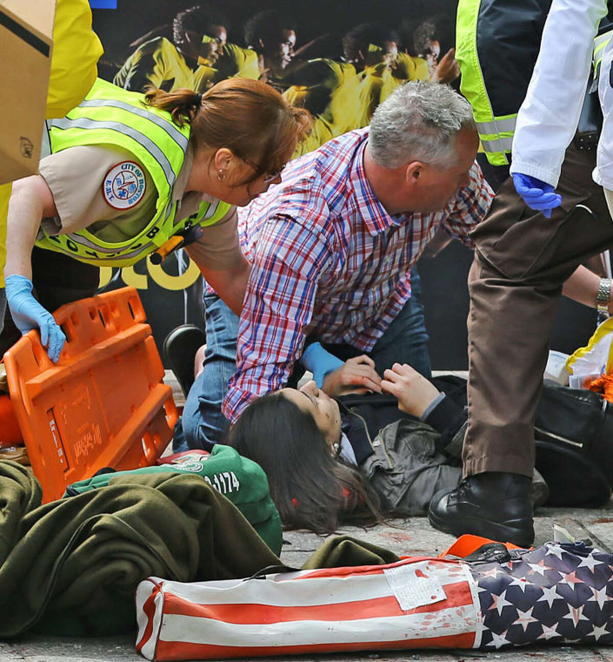 Medical workers aid injured people at the 2013 Boston Marathon following an explosion in Boston, Monday, April 15, 2013. Two explosions shattered the euphoria of the Boston Marathon finish line on Monday, sending authorities out on the course to carry off the injured while the stragglers were rerouted away from the smoking site of the blasts. (AP Photo/The Boston Globe, David L Ryan)