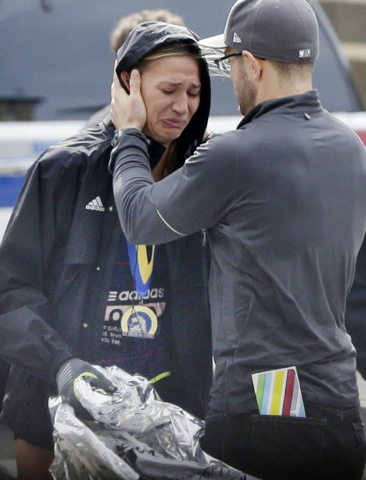 An unidentified Boston Marathon runner is comforted as she cries in the aftermath of two blasts which exploded near the finish line of the Boston Marathon in Boston, Monday, April 15, 2013. (AP Photo/Elise Amendola)