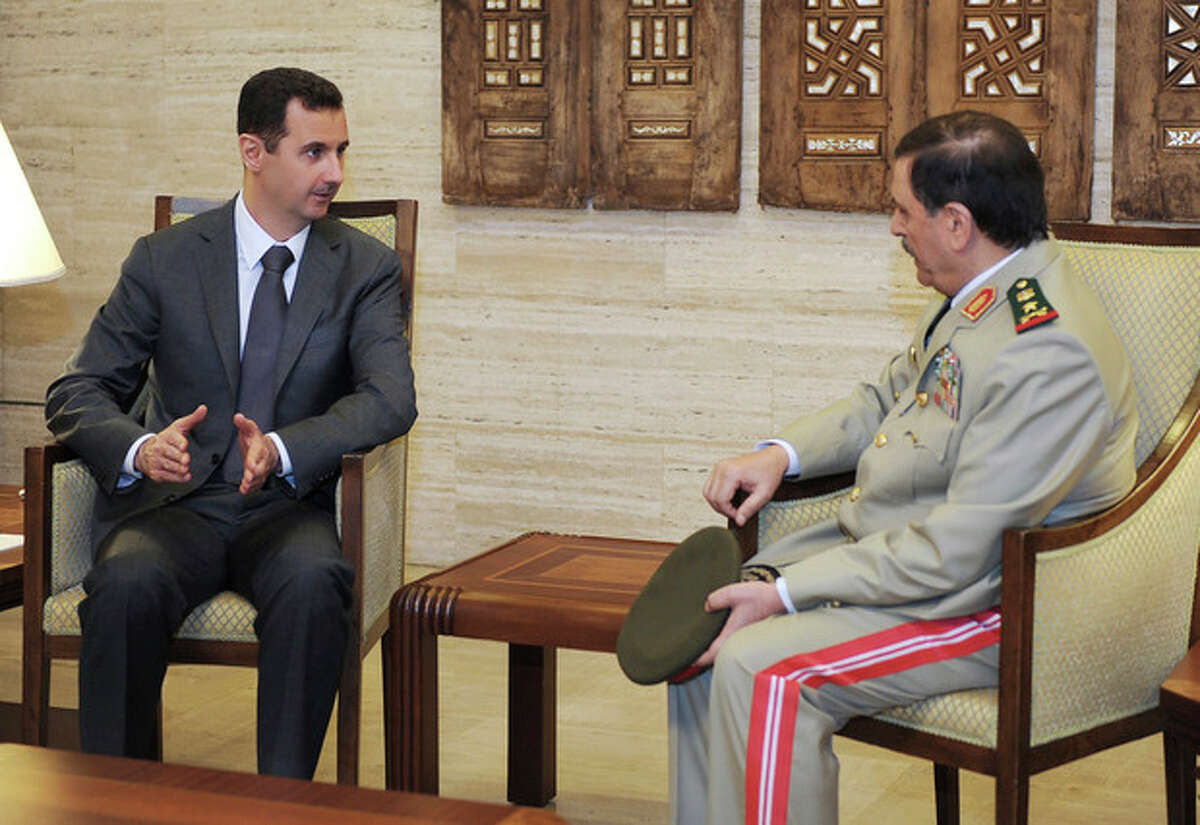 FILE - In this file photo released by the Syrian official news agency SANA on July 19, 2012, Syrian President Bashar Assad, left, meets with Fahd Jassem al-Freij, Syria's new Defense Minister, in Damascus, Syria. In the recent sectarian violence in Syria, some observers see a grim pattern: Alawite fighters from President Bashar Assad's minority sect trying to carve out a breakaway region for themselves by driving out local Sunnis, killing entire families and threatening anybody who stays behind. If the regime falls, the Alawite heartland on Syria?’s mountainous coast could become a refuge for the community and even Assad himself to fight for survival against the Sunni majority. (AP Photo/SANA, File)