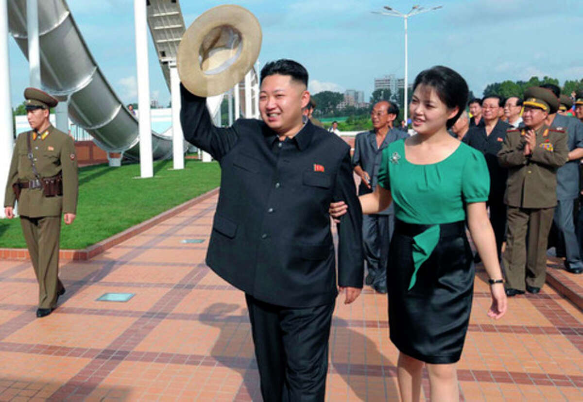 In this Wednesday, July 25, 2012 photo released by the Korean Central News Agency (KCNA) and distributed in Tokyo by the Korea News Service Thursday, July 26, 2012, North Korean leader Kim Jong Un, center, accompanied by his wife Ri Sol Ju, right, waves to the crowd as they inspect the Rungna People's Pleasure Ground in Pyongyang. (AP Photo/Korean Central News Agency via Korea News Service) JAPAN OUT UNTIL 14 DAYS AFTER THE DAY OF TRANSMISSION