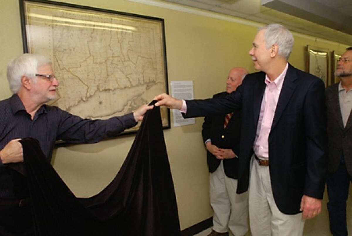 Bob Weingarten, House Research Director at the Westport Historical Society, and Robert Augustyn of Martayan Lan Augustyn Inc. unveil an antique map found by Westporter Carles Reedy, far right, at Town Hall Wednesday while First Selectman Gordon Joseloff looks on. The historic 1812 map of Connecticut whose restoration was funded by Martayan Lan Augustyn Inc. was hung on the first floor of Westport Town Hall outside the Town Clerks office. Hour photo / Erik Trautmann