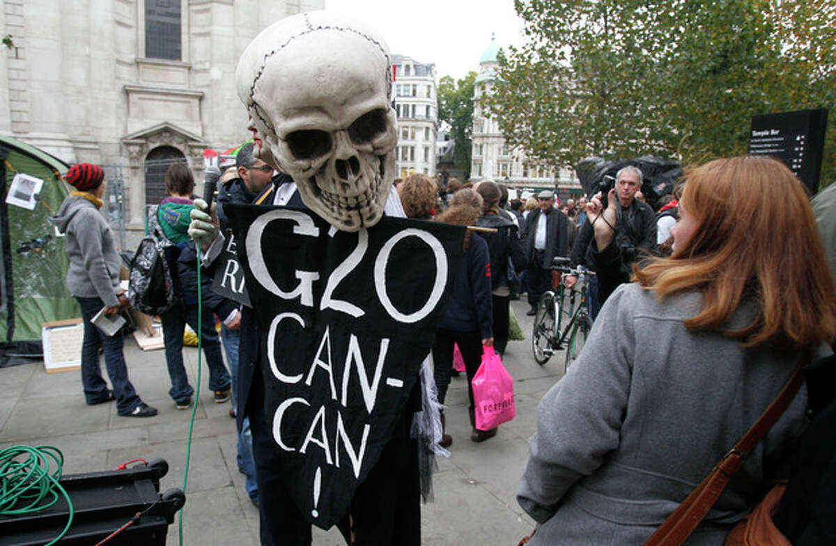A woman reacts as a protestor wearing a skeleton mask walks past her outside St. Paul's Cathedral in London, Monday, Oct. 31, 2011. The Dean of St. Paul's Cathedral in London on Monday became the second high-profile clergy member to step down amid mounting controversy over anti-capitalist protests on the church's grounds. (AP Photo/Kirsty Wigglesworth)