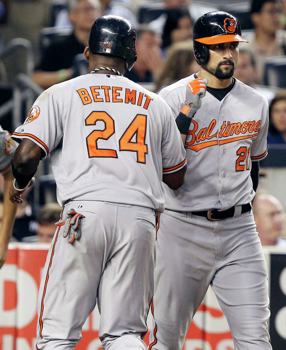 Baltimore Orioles' Nick Markakis, right, greets Wilson Betemit after Betemit scored on a hit by Omar Quintanilla during the fifth inning of a baseball game against the New York Yankees, Monday, July 30, 2012, at Yankee Stadium in New York. (AP Photo/Seth Wenig)