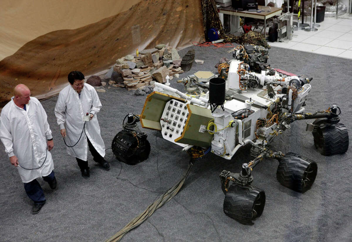 Engineers work on a model of the Mars rover Curiosity at the Spacecraft Assembly Facility at NASA's Jet Propulsion Laboratory in Pasadena, Calif., Thursday, Aug. 2, 2012. After traveling 8 1/2 months and 352 million miles, Curiosity will attempt a landing on Mars the night of Aug. 5, 2012. (AP Photo/Damian Dovarganes)