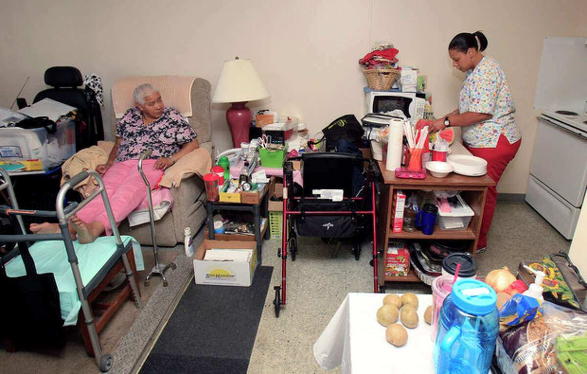 In this Aug. 1, 2012 photo, Taura Tate, right, a home care aide since 1999, prepares food for Crell Johnson, 76, at Johnson's apartment in Euclid, Ohio. For the past three years, she has spent four hours each weekday morning caring for Johnson, who suffered a stroke and has diabetes. Tate cooks Johnson's oatmeal for breakfast, helps her shower and watches to make sure she takes the right medicine. (AP Photo/Tony Dejak)