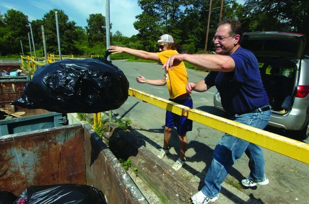 File Photo/ Alex von Kleydorff. Wilton's Joe DeGirolamo and son Chris chuck the spoiled contents of their refridgerator and freezer into a container at the Wilton Transfer Station. The family lost power last summer during Tropical Storm Irene.