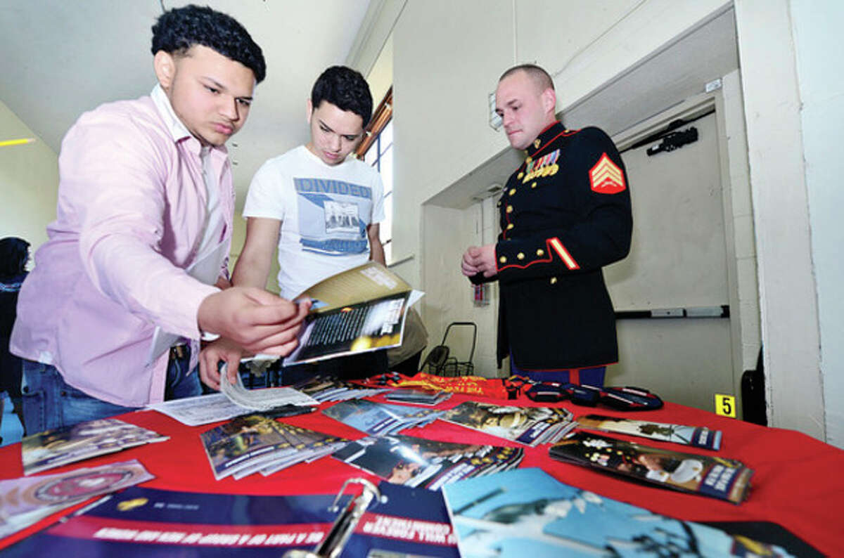 Hour photo / Erik Trautmann Richard Tanales and Jean-Claude Villa get literature from Marine Corps and marine seargent Michael Torrwes during the Briggs High School Career Fair Thursday morning.