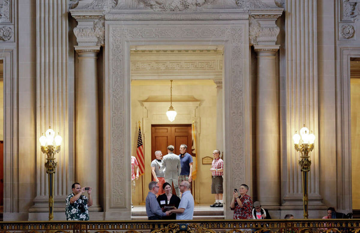 Gay couples, including Andy Uri, in long sleeve shirt, and Joe Taus, bottom center, of Portland, Ore., exchange wedding vows at City Hall in San Francisco, Saturday, June 29, 2013. Dozens of gay couples waited excitedly Saturday outside of San Francisco's City Hall as clerks resumed issuing same-sex marriage licenses, one day after a federal appeals court cleared the way for the state of California to immediately lift a 4 ½ year freeze. Big crowds were expected from across the state as long lines had already stretched down the lobby shortly after 9 a.m. City officials decided to hold weekend hours and let couples tie the knot as San Francisco is also celebrating its annual Pride weekend expected to draw as many as 1 million people. (AP Photo/Marcio Jose Sanchez)