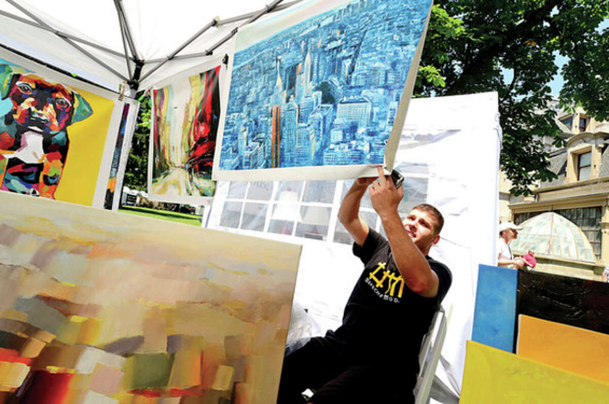 Hour photos / Erik Trautmann Above, Willy Biaggi hangs his art during the first Norwalk Art Festival at Mathews Park Saturday. Below, Marge Kitchens and Shirlie Kemsek look at the Fantasy Dolls by Kathy Pilipauskas during the art festival.