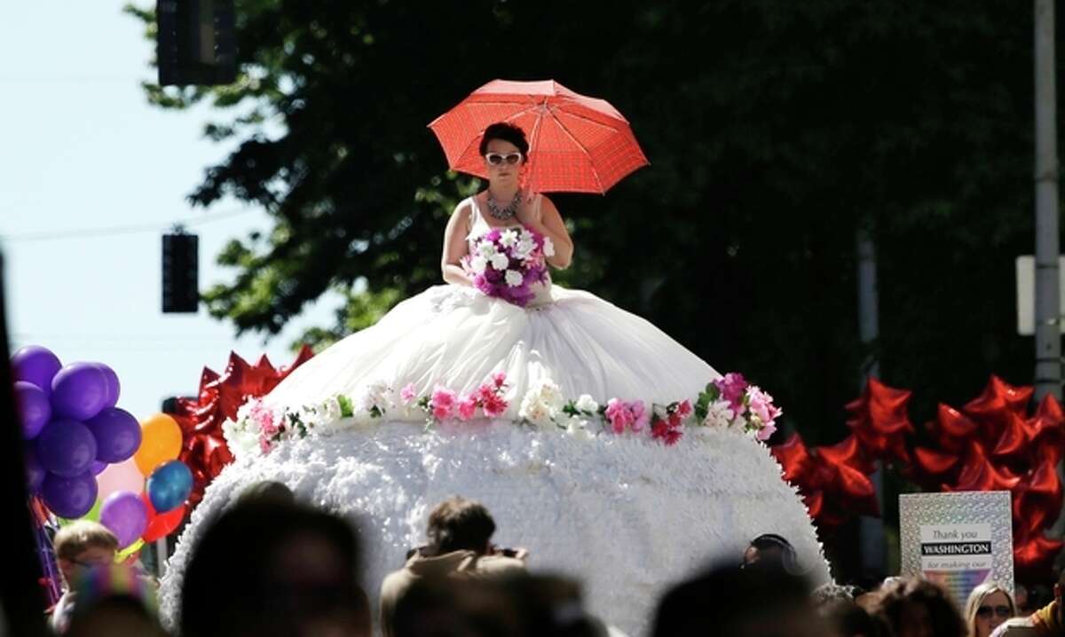 Erika Locatelli stands atop a hoop-style wedding gown float as she is pulled along the parade route of the annual Gay Pride parade Sunday, June 30, 2013, in Seattle. (AP Photo/Elaine Thompson)