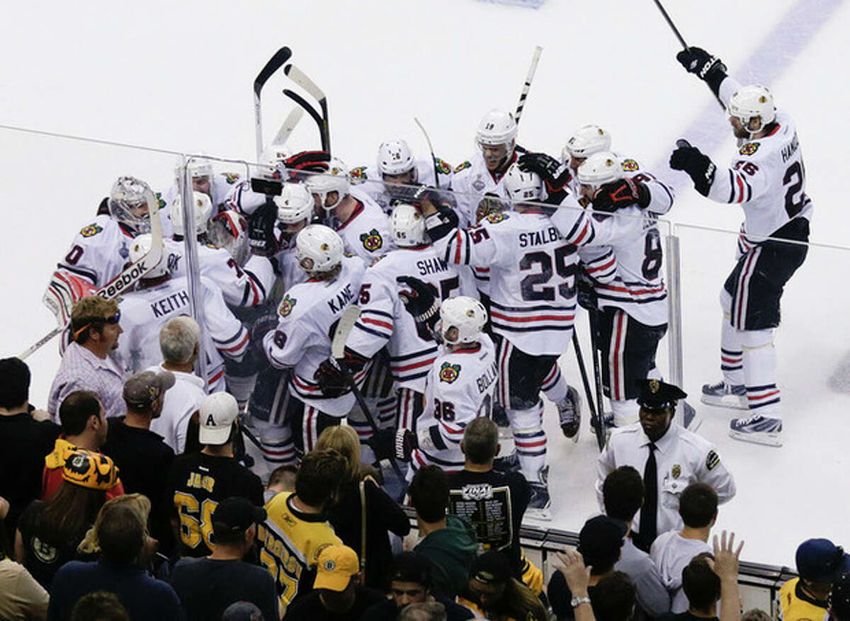 The Chicago Blackhawks mob Brent Seabrook, after his game-winning goal against the Boston Bruins during the first overtime period in Game 4 of the NHL hockey Stanley Cup Finals, Wednesday, June 19, 2013, in Boston. Chicago won 6-5. (AP Photo/Charles Krupa)