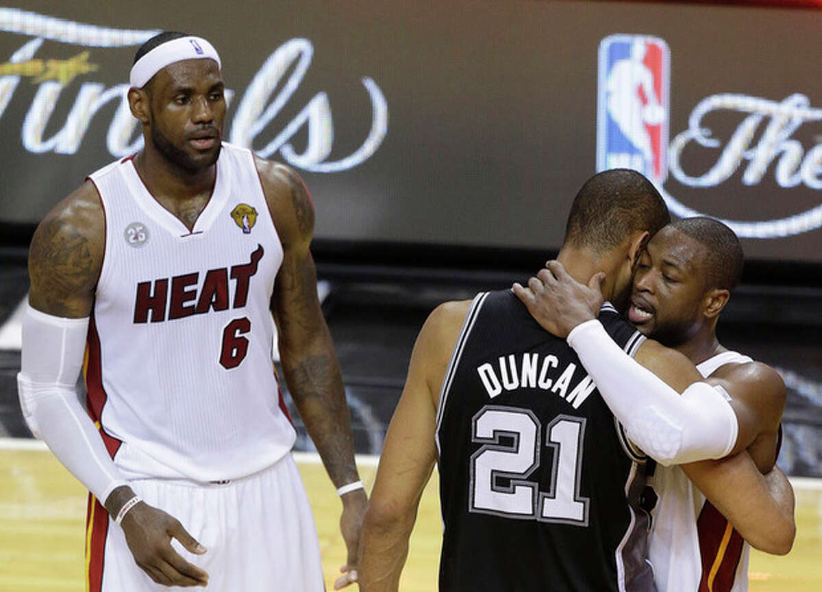The San Antonio Spurs' Tim Duncan (21) embraces Miami Heat's Dwyane Wade (3) as Miami Heat's LeBron James (6) looks on after the second half in Game 7 of the NBA basketball championship, early Friday morning, June 21, 2013, in Miami. The Miami Heat defeated the San Antonio Spurs 95-88 to win their second straight NBA championship. (AP Photo/Steve Mitchell, Pool)
