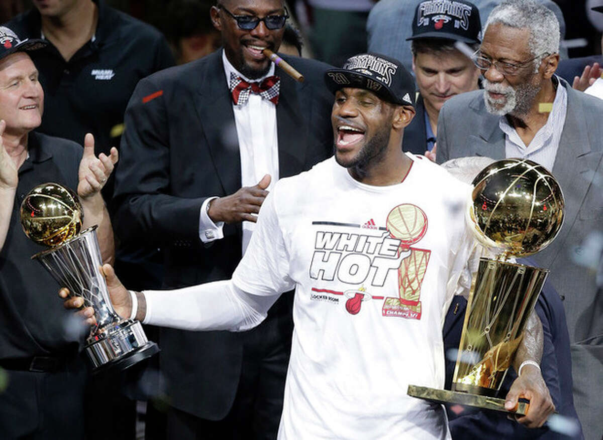 The Miami Heat's LeBron James, left, holding the Larry O'Brien NBA Championship Trophy and his Bill Russell NBA Finals Most Valuable Player Award after Game 7 of the NBA basketball championship game against the San Antonio Spurs, Friday, June 21, 2013, in Miami. The Miami Heat defeated the San Antonio Spurs 95-88 to win their second straight NBA championship. Former NBA player Bill Russell looks on. (AP Photo/Wilfredo Lee)