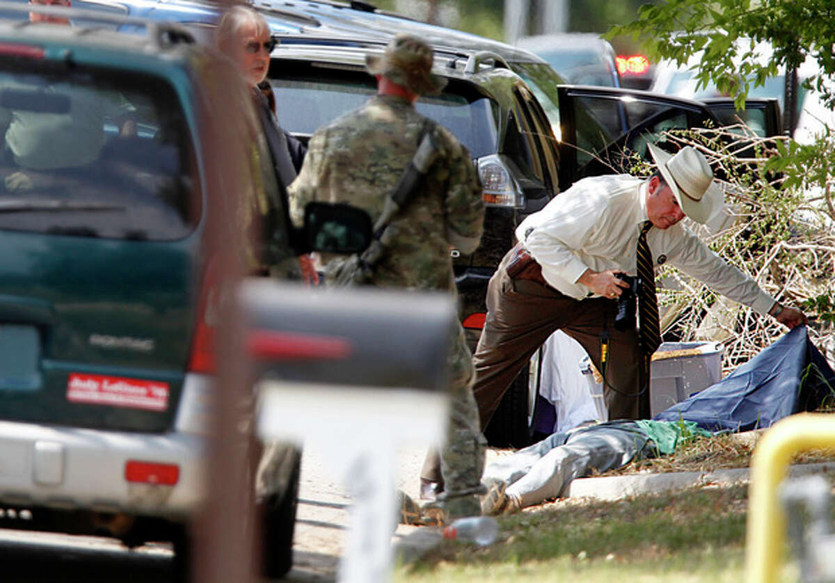 An investigator uncovers a body at the scene where a gunman opened fire on a police officer serving an eviction notice near the Texas A&M University on Monday, Aug. 13, 2012, in College Station, Texas. College Station Assistant Police Chief Scott McCollum says Brazos County Constable Brian Bachmann was among three people, including the gunman, killed in the shootout. (AP Photo/Houston Chronicle, Mayra Beltran) MANDATORY CREDIT: NO SALES, MAGS OUT, TV OUT, INTERNET: AP MEMBERS ONLY