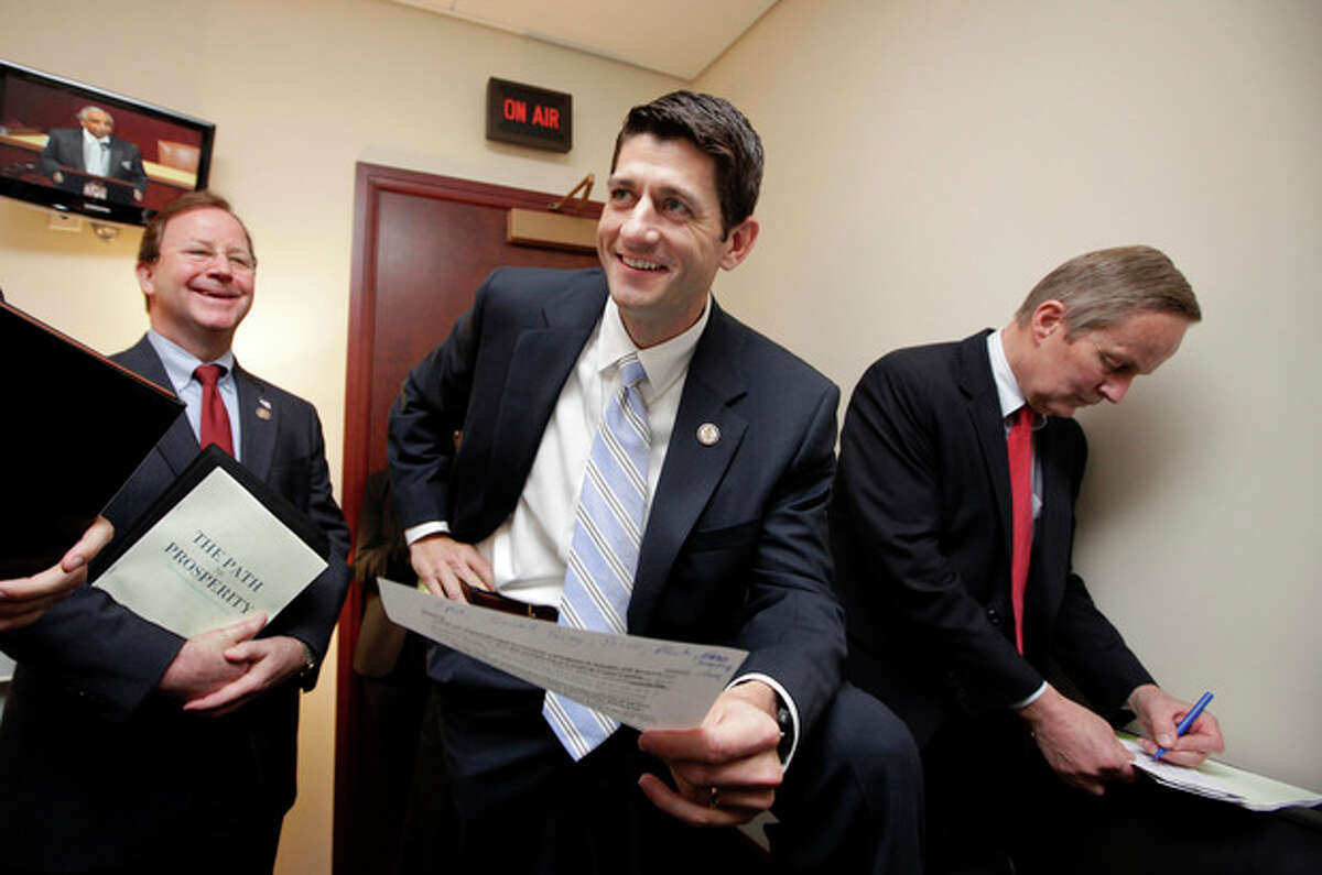 FILE - In this April 5, 2011 file photo, Republican Vice Presidential candidate, House Budget Committee Chairman Paul Ryan, R-Wis., works with Republican members of the committee on Capitol Hill in Washington before introducing his Path to Prosperity. At right is Rep. Todd Akin, R-Mo., with Rep. Bill Flores, R-Texas, at left. Paul Ryan traveled a perilous route to political stardom. While other lawmakers nervously whistled past trillion-dollar deficits, fearing to cut popular programs, he waded in with a machete and a smile. Ryan wants to slice away at Medicare, Social Security, food stamps and virtually every other government program but the military. (AP Photo/J. Scott Applewhite, File)