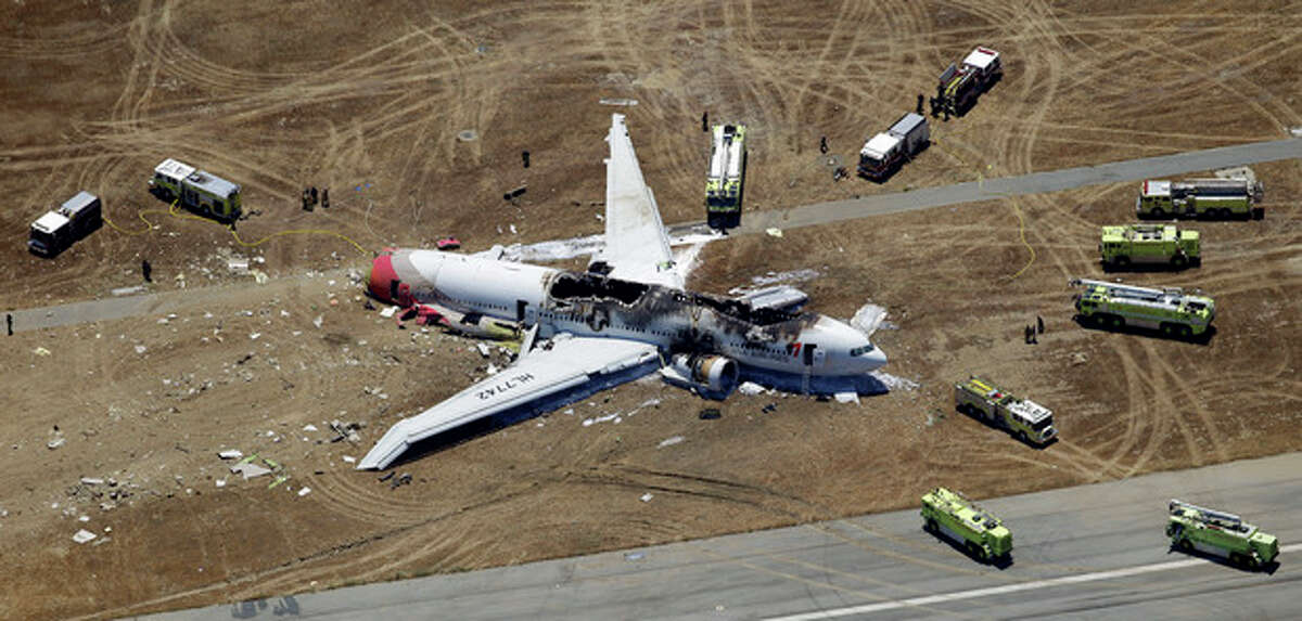 FILE - This July 6, 2013, file photo shows the wreckage of Asiana Flight 214 on the ground after it crashed at the San Francisco International Airport, in San Francisco. When the courts have to figure compensation for people aboard Flight 214, the potential payouts will probably be vastly different for Americans and passengers from other countries. A pact is likely to close U.S. courts to many foreigners and force them to pursue their claims in Asia and elsewhere, where lawsuits are rarer, harder to win (AP Photo/Marcio Jose Sanchez, File)