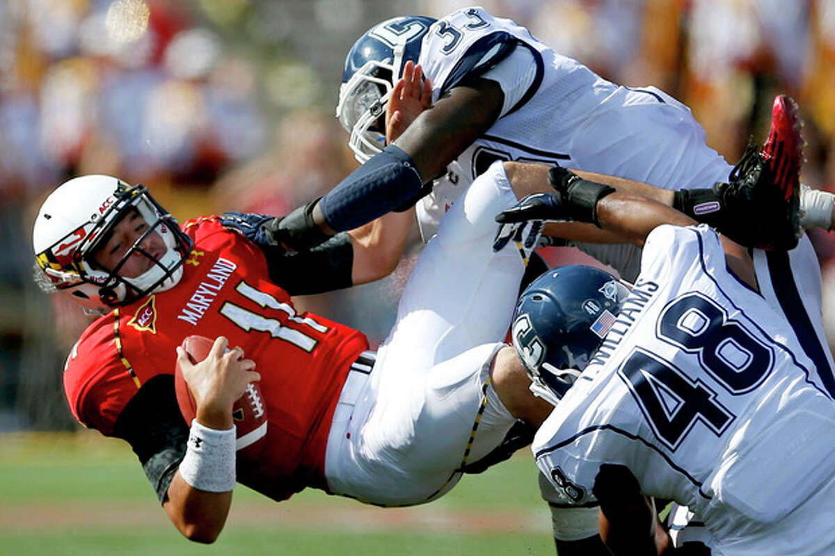 Maryland quarterback Perry Hills (11) is tackled by Connecticut's Yawin Smallwood, top right, and Trevardo Williams in the second half of an NCAA college football game in College Park, Md., Saturday, Sept. 15, 2012. Connecticut won 24-21. (AP Photo/Patrick Semansky)