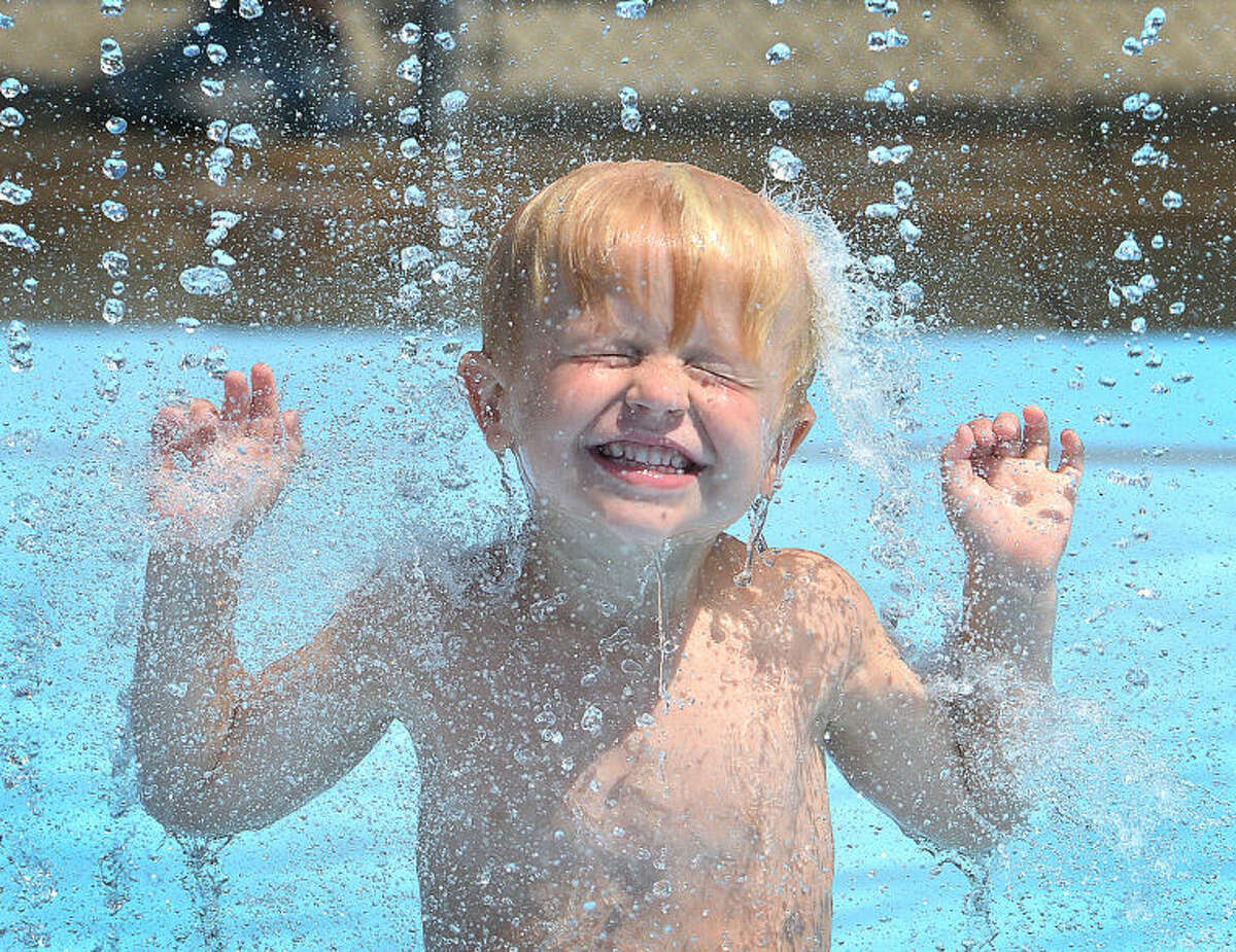 Hour Photo/Alex von Kleydorff. 4yr old Philip Jeschke stays cool under the waterfall tower in the splash pool at The Wilton Family Y on Tuesday. With temeratures near 100 degrees, the Y was one of the coolest places in town