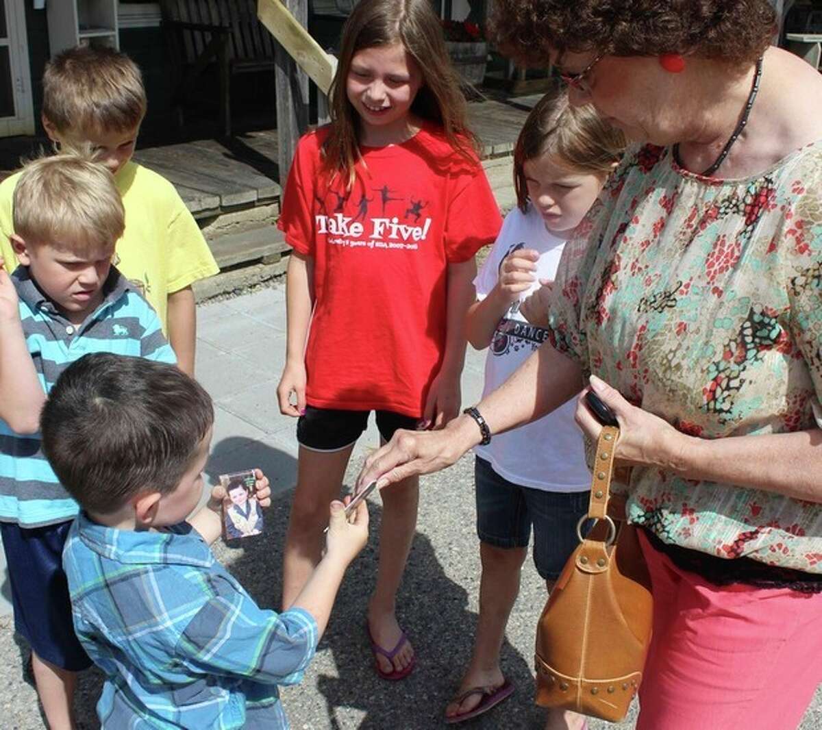 In this photo made Wednesday, June 26, 2013 in Dorset , Minn., Bobby Tufts, the 4-year-old mayor, hands out his card to potential voters for his re-election bid. Bobby was only 3 when he won election last year as mayor of Dorset (population 22 to 28, depending on whether the minister and his family are in town). Dorset, which bills itself as the Restaurant Capital of the World, has no formal city government. (AP Photo/Jeff Baenen)
